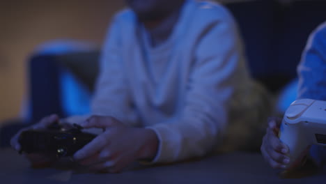 Nahaufnahme-Von-Zwei-Kleinen-Jungen-Zu-Hause,-Die-Spät-In-Der-Nacht-Mit-Einer-Computerspielkonsole-Im-Fernsehen-Spielen-Und-Controller-Halten-5