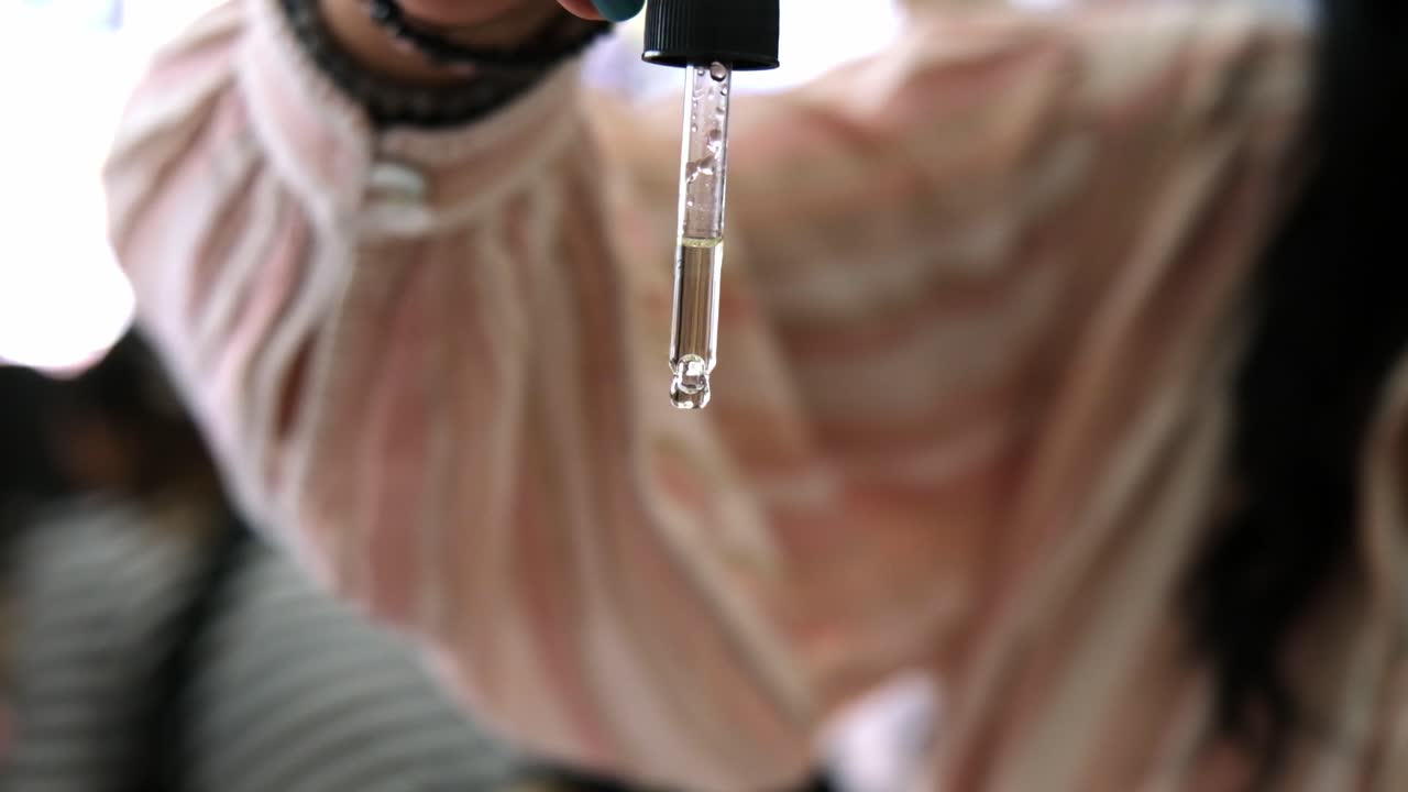 el aceite natural goteando en cámara lenta desde la pipeta a la palma de la hembra