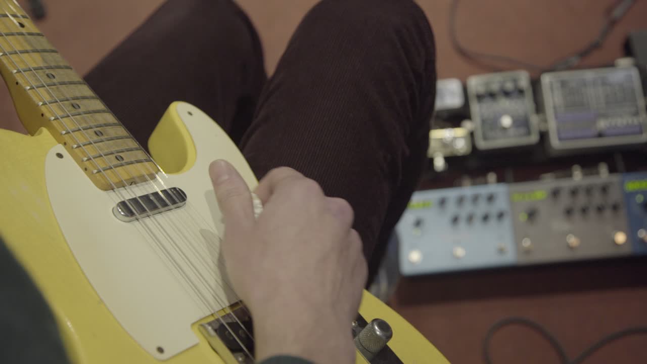 Close up of musician playing on retro yellow electric guitar in studio.