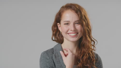 Head-And-Shoulders-Studio-Portrait-Of-Laughing-Young-Businesswoman-Against-Plain-Background