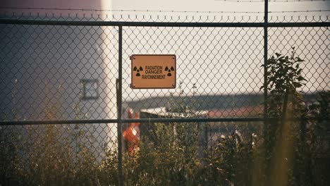 wide shot of radiation danger sign in exclusion zone barbed wire perimeter fence in slow motion 4k