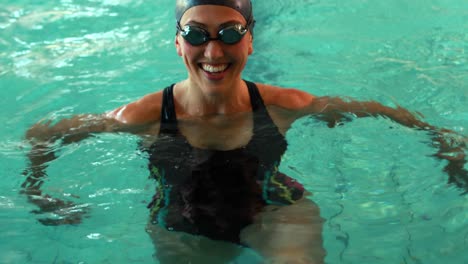 fit swimmer smiling at camera in the swimming pool