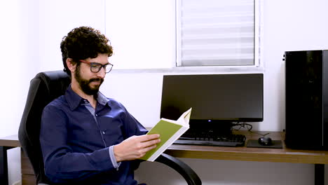 man finishes reading a green book at home office