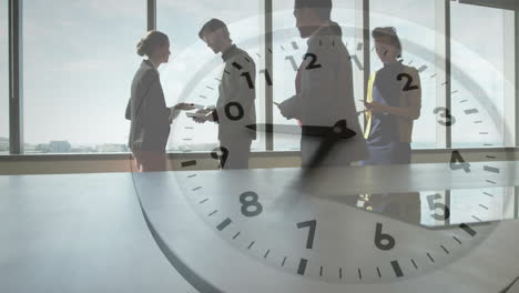 Animation-of-clock-moving-over-diverse-colleagues-talking-in-office