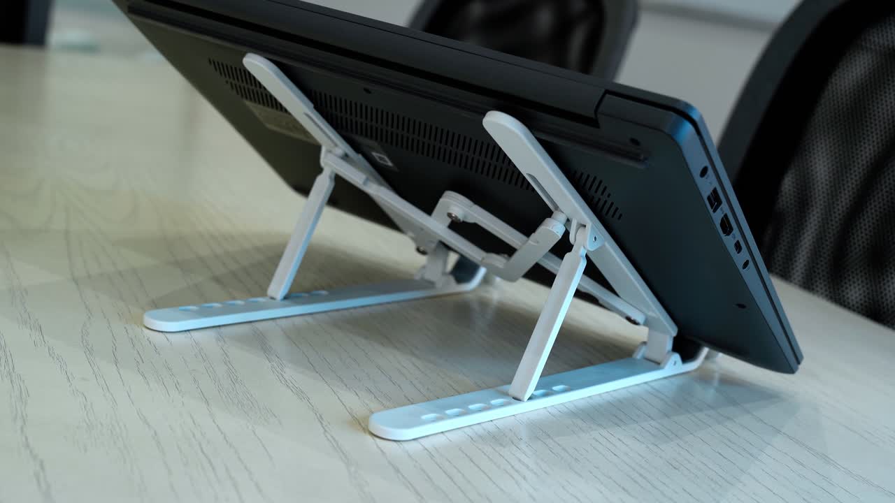 Close-up of hand setting up laptop on adjustable stand—ideal for tech, productivity, and modern office visuals.
