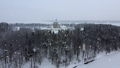 snow covered pazaislis monastery during heavy snowstorm day, drone ascend view