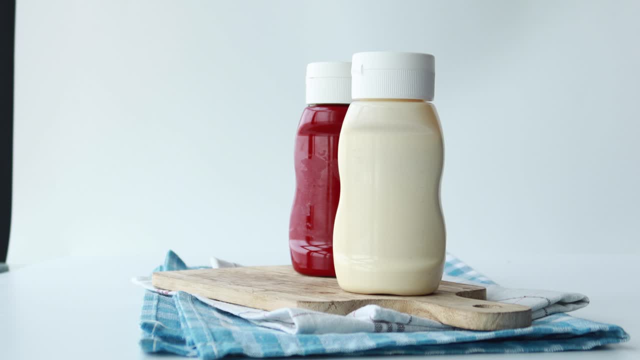 botellas de ketchup y mayonesa en una tabla de cortar