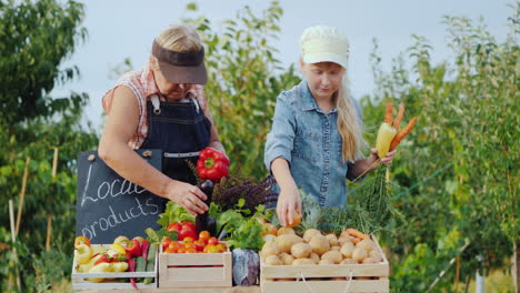 abuela y nieta ponen verduras en el mostrador del mercado de agricultores