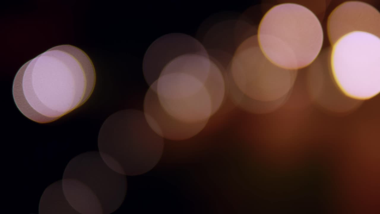 Bokeh-baggrund af skyskraberbygninger i byen med lys og slørede, farverige lyscirkler om natten