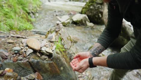 man drinking from a mountain stream