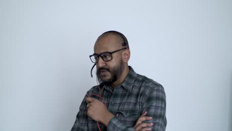 A-close-up-shot-of-a-remote-Asian-IT-professional-anxiously-pacing-around-his-office-while-talking-into-his-headset,-the-man-communicating-with-his-colleague-as-they-troubleshoot-a-technical-issue