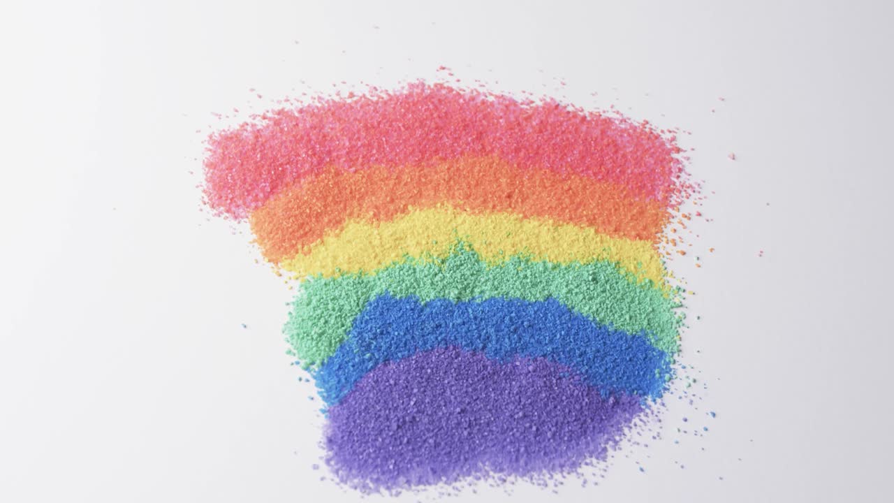 Video of close up of rainbow coloured sand grains and copy space on white background
