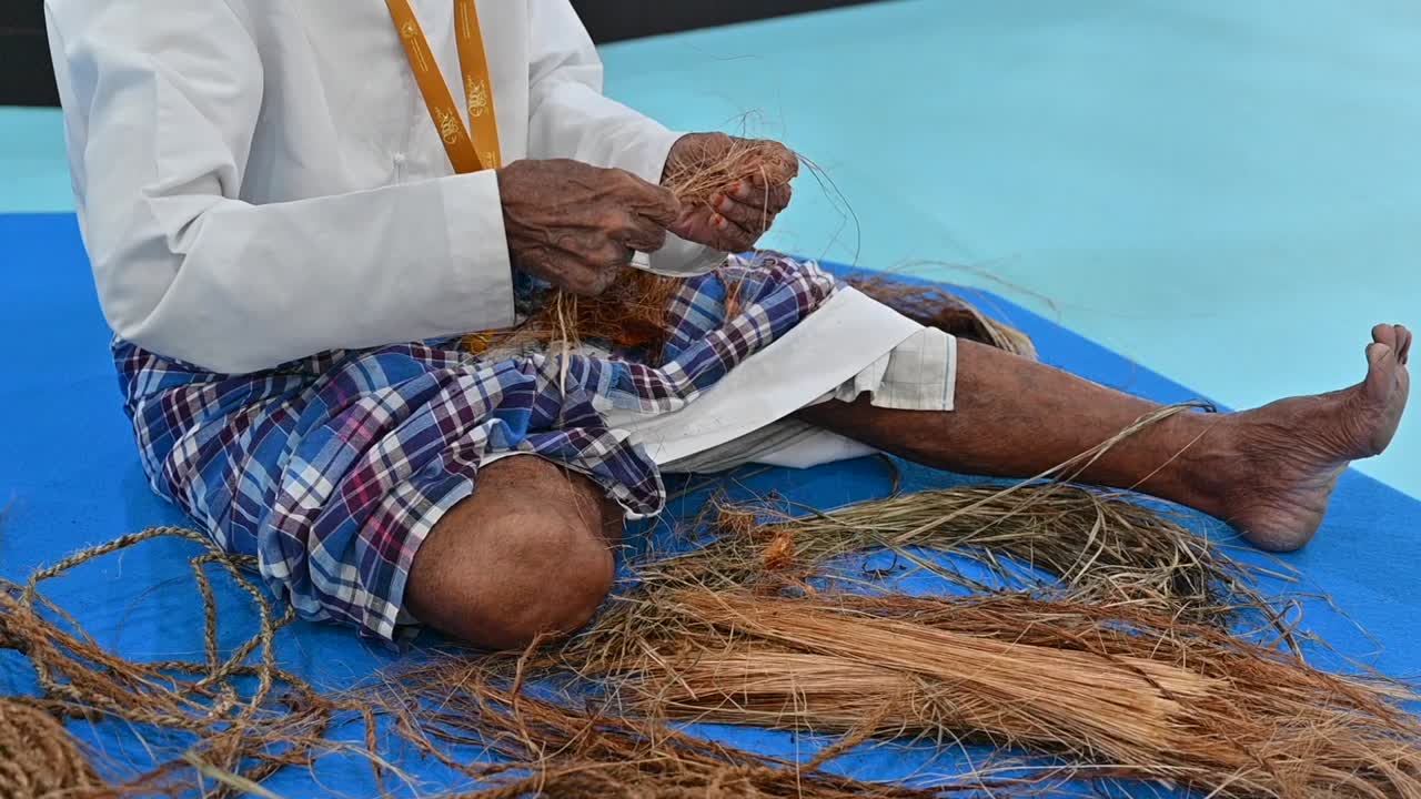 un pescador árabe haciendo una cuerda usando su mano con fibras de palma