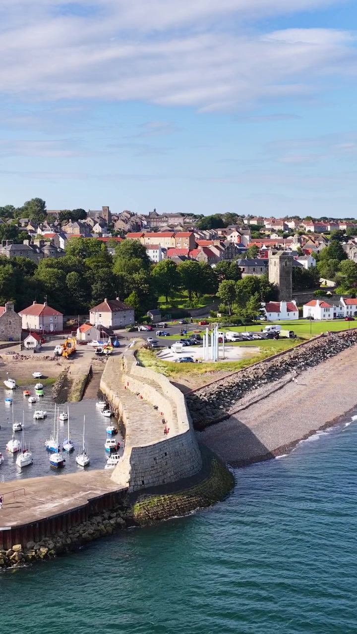 Un drone sorvola una città costiera, case fronte mare, un porto e la costa in pieno giorno.