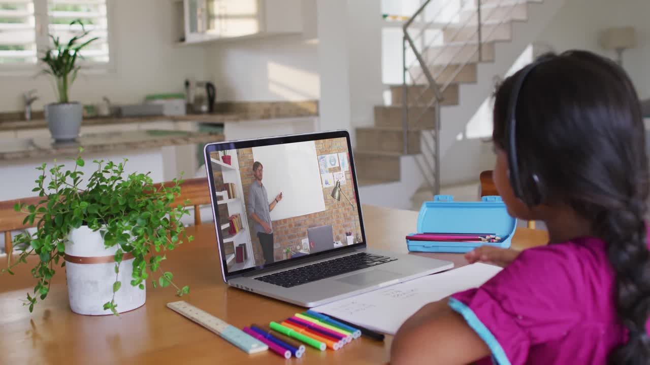 chica afroamericana haciendo la tarea mientras tiene una videollamada con un profesor masculino en una computadora portátil en casa