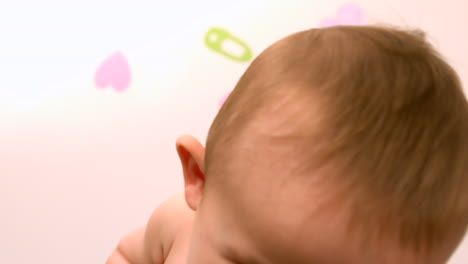 Baby-sitting-in-crib-smiling-at-camera