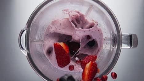 adding berries blending smoothie in super slow motion closeup. natural milkshake