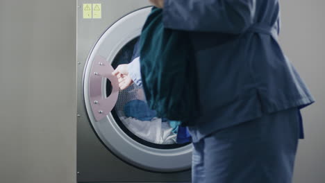 Female-worker-doing-laundry.-Pick-up-uniform-from-washing-drum