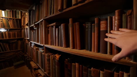 hand selecting a book from an old library bookshelf