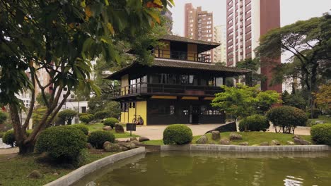 a traditional asian house amidst an exuberant city, surrounded by lots of trees in a calm and quiet environment, creating a perfect place to relax