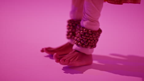 cerca de los pies y las campanas de la bailarina de kathak femenina que realiza el baile vestida con el vestido tradicional indio contra un fondo púrpura 4