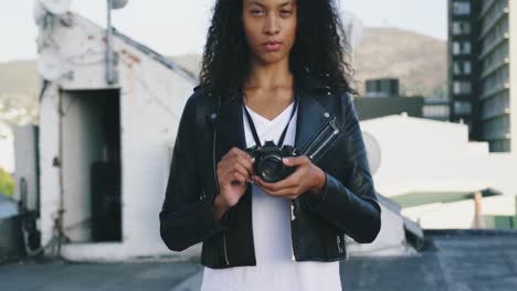 fashionable young woman on urban rooftop holding a camera