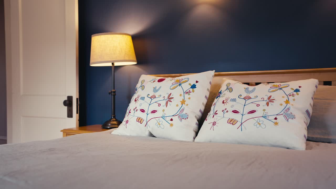 푸른 벽 앞에 있는 나이트 스테이크에 램프가 있는 예술적 디자인의  베드와 함께  기둥