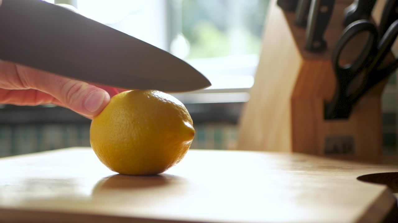 Slow motion shot of a lemon being sliced in half