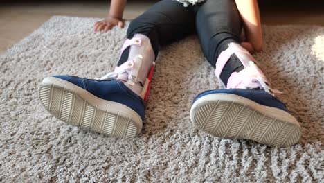 child with leg brace sitting on carpet
