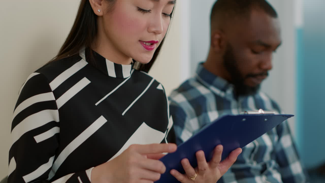 Female candidate looking at recruitment files in queue at job interview