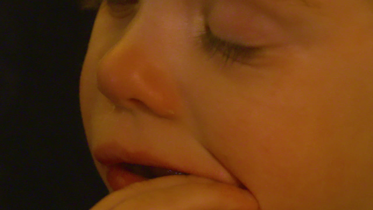 un primerísimo plano de una linda niña comiendo un bocadillo mientras ve la televisión