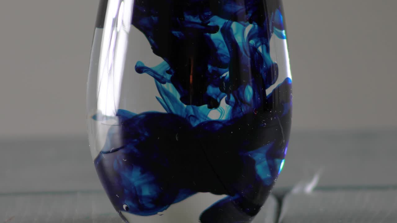 крупный план синего пищевого красителя, опущенного в воду