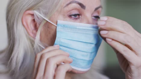 Portrait-of-senior-caucasian-woman-at-home-adjusting-her-face-mask