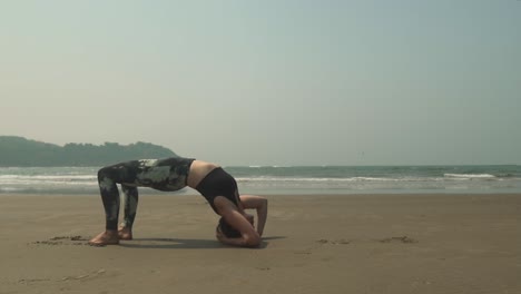 Chica-Haciendo-Posición-De-Yoga-En-La-Parte-Superior-De-La-Mesa-Doblada-Hacia-Atrás-En-La-Arena-En-Una-Ubicación-Costera