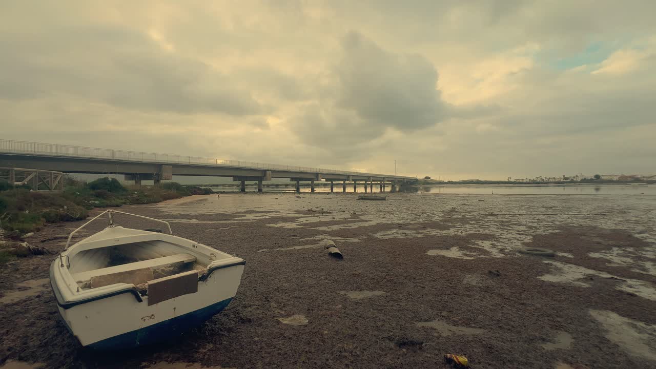 un time-lapse captura un viejo barco descansando en las costas arenosas de una tranquila zona costera, encarnando la esencia de la nostalgia y el patrimonio marítimo