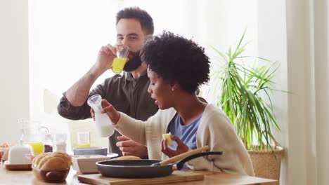 Video-Eines-Glücklichen,-Vielfältigen-Paares,-Das-Am-Frühstückstisch-Isst-Und-Trinkt