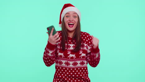 Adult-girl-in-red-Christmas-sweater-looking-smartphone-display-sincerely-rejoicing-win-success-luck