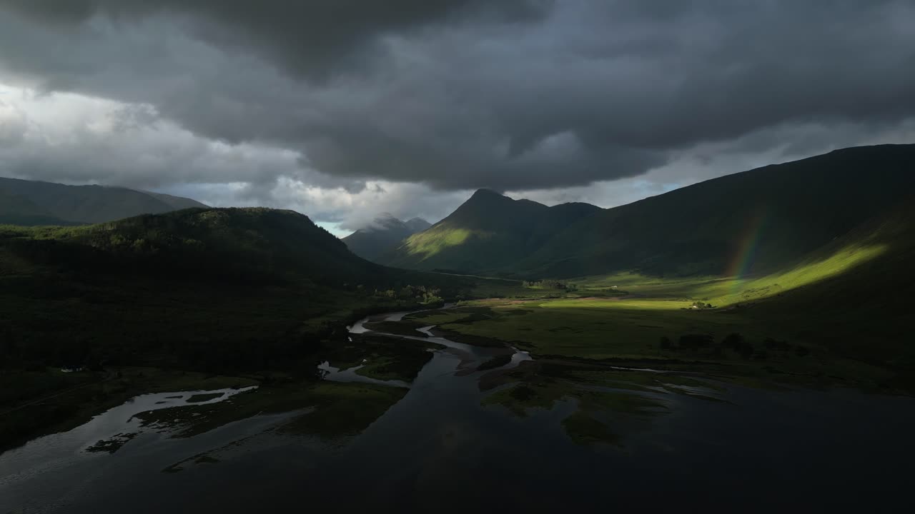 Cinematic aerial drone footage of a rainbow over Loch Etive in the Scottish Highlands showing dramatic mountain landscape and natural scenery