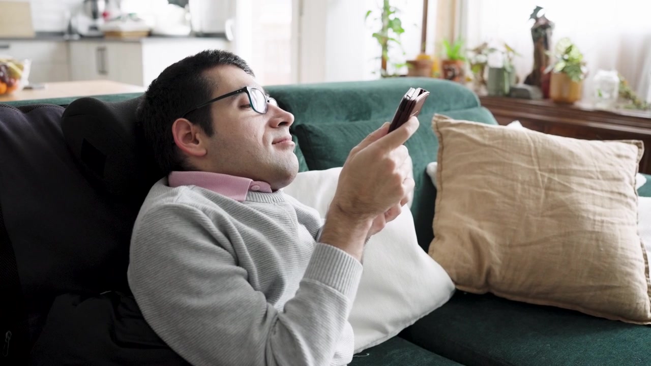 Giovane uomo che si rilassa sul divano e usa lo smartphone a casa