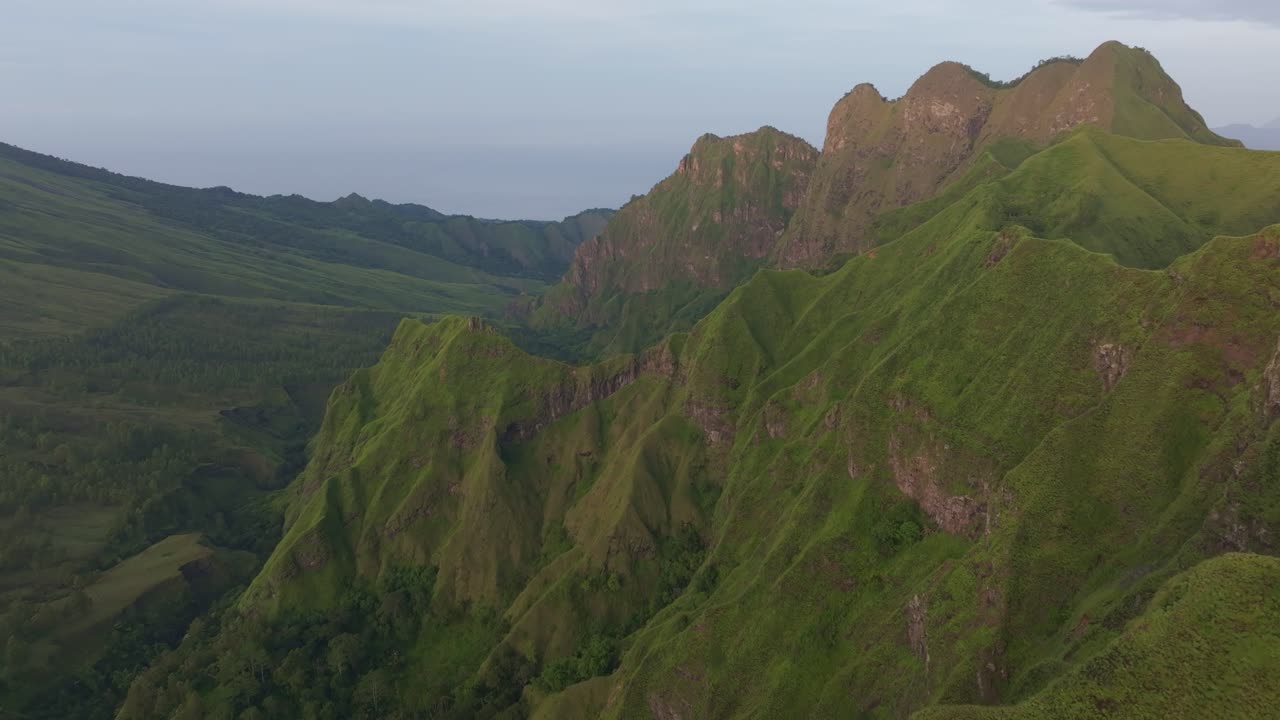 Cahaya pagi di puncak gunung berapi dan hamparan hutan di sekitarnya, Flores, Indonesia.