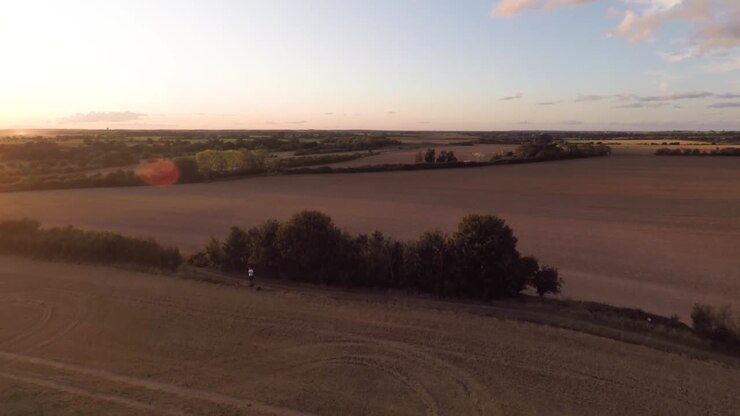 Slowly descending down towards a harvested field while looking out over a summer sunset-1