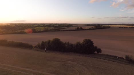 Langsam-Hinab-Zu-Einem-Abgeernteten-Feld,-Während-Sie-Auf-Einen-Sommersonnenuntergang-Blicken-1