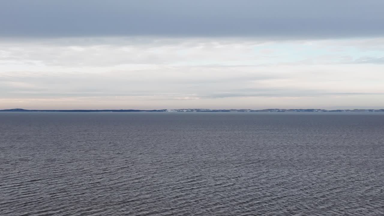 A panoramic view of the vast Curonian Lagoon, with a barely visible sandbank, captured at sunset during wintertime. Europe Lithuania.