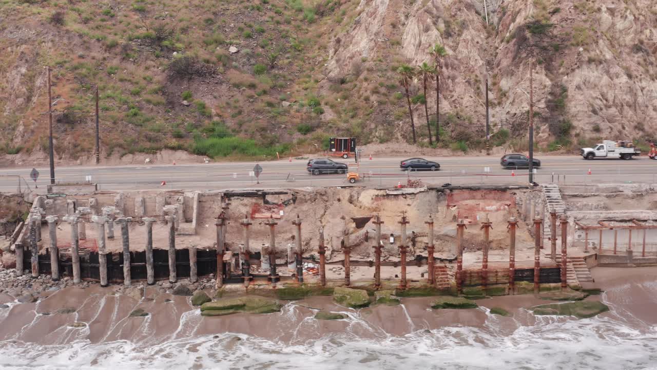Dolly close-up aerial shot of burned oceanfront residential lots along the Pacific Coast Highway after the Palisades Fire in Southern California. 4K