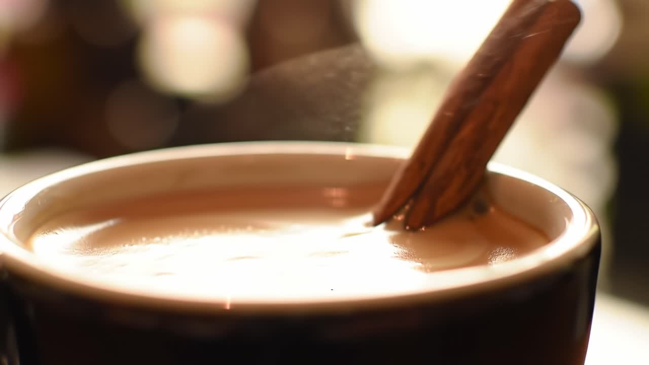 A Close-Up of Simmering Beverage with Cinnamon Stick Stirring, Capturing the Warmth and Aroma of a Cozy Moment