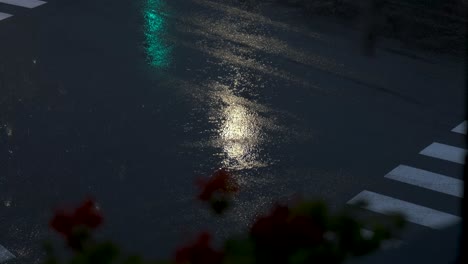 Cars-passing-by-a-crossroad-under-a-summer-rain-storm-shot-from-a-balcony