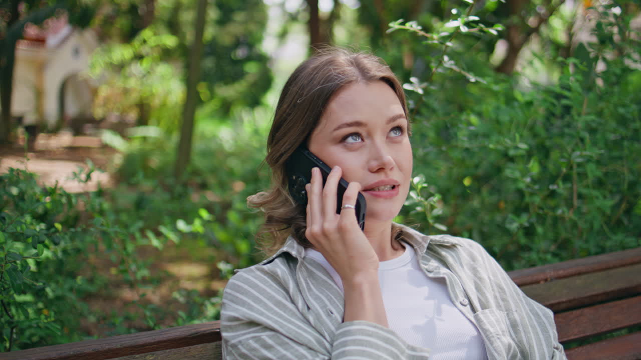 Relaxed girl talking cellphone contemplating green park closeup. Happy woman