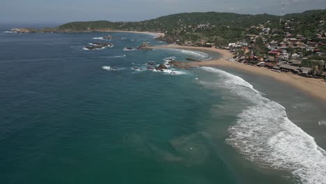 Flyover:-Serene-crescent-sand-beaches,-ocean-waves-in-MX-seaside-town