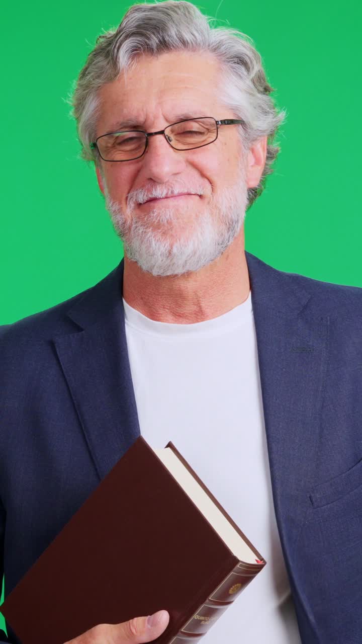 Uomo anziano sorridente che tiene in mano un libro su schermo verde