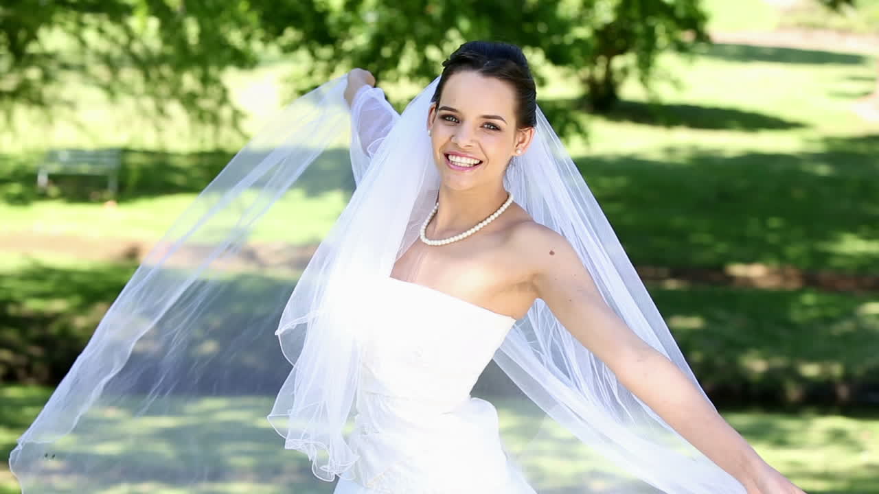 Bella sposa che sorride alla macchina fotografica nel parco